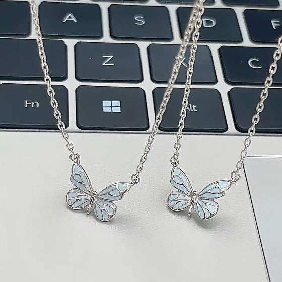 Two butterfly pendant necklaces on a laptop keyboard, not included