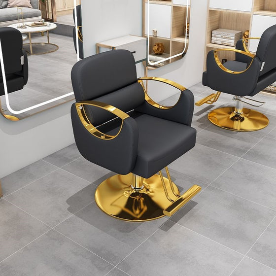 Black salon chair with gold armrests and base in a salon