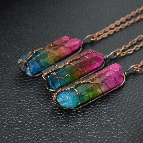 Three rainbow crystal tree of life pendants on a dark background