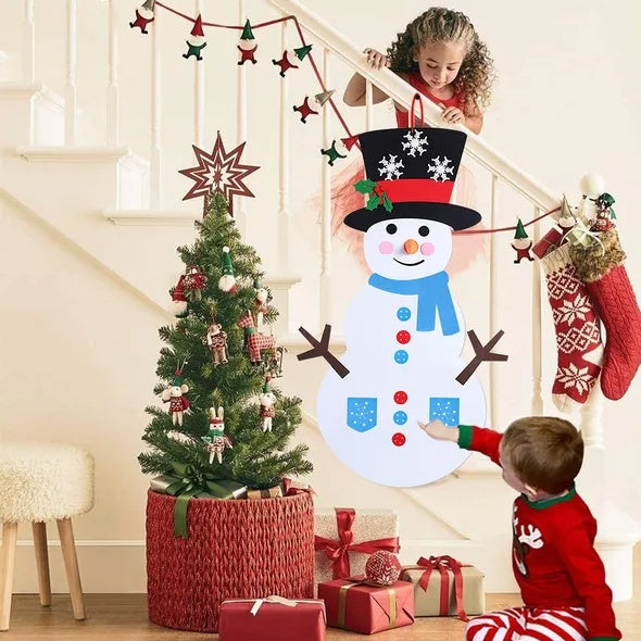 Children decorating a DIY felt snowman on a wall beside a Christmas tree