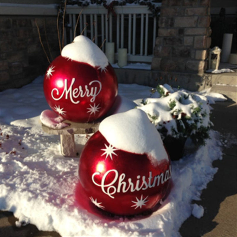 Two giant red inflatable Merry Christmas ornament balls in the snow