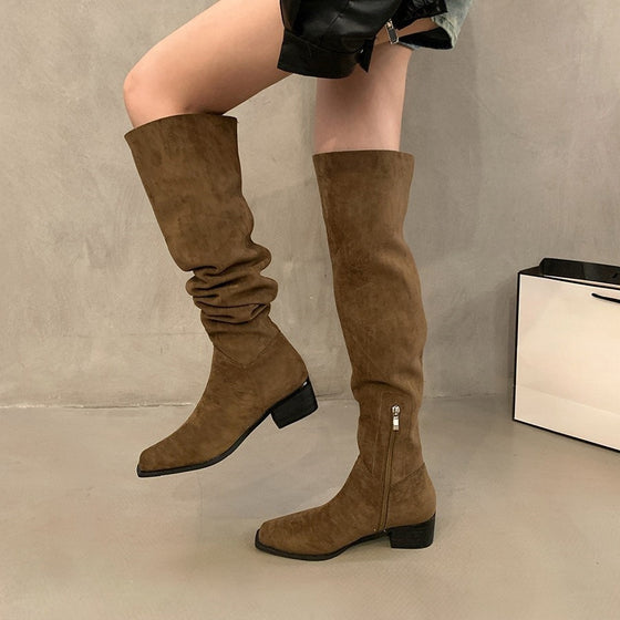 Brown slouchy suede boots with a block heel worn with a leather skirt