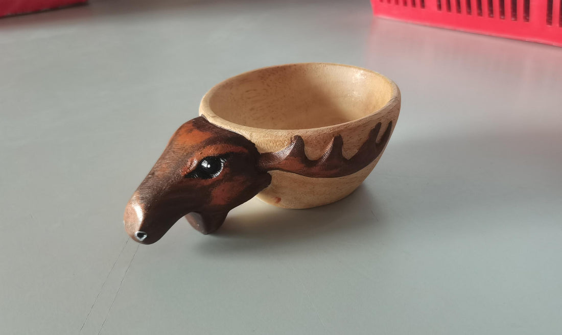 Kuksa wooden mug with carved moose head handle on a grey table