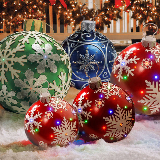 Giant inflatable Christmas ornament balls in green, blue and red snowflake patterns on a snowy porch