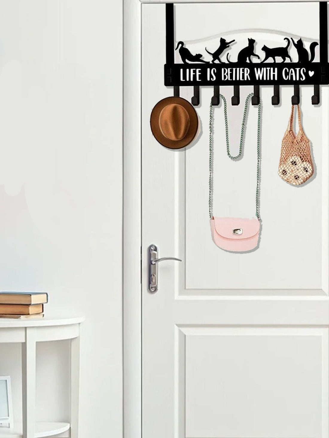 Cat hook rack holding a hat, bag and tote on a white door