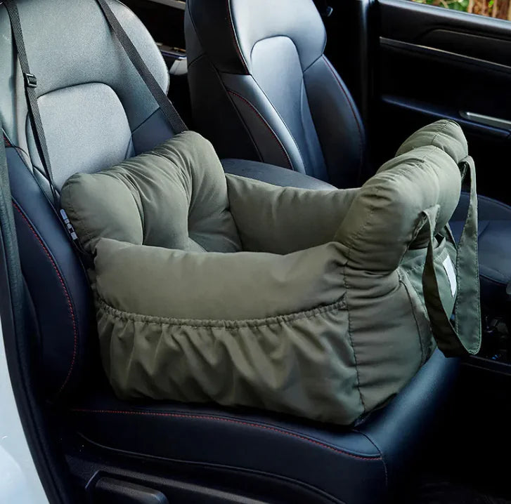 Padded olive-green pet booster car seat with raised side bolsters, a front storage pocket, and a seatbelt-loop mount