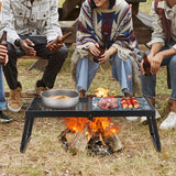Black folding campfire grill with a flat griddle section and a wire grate section over an open flame