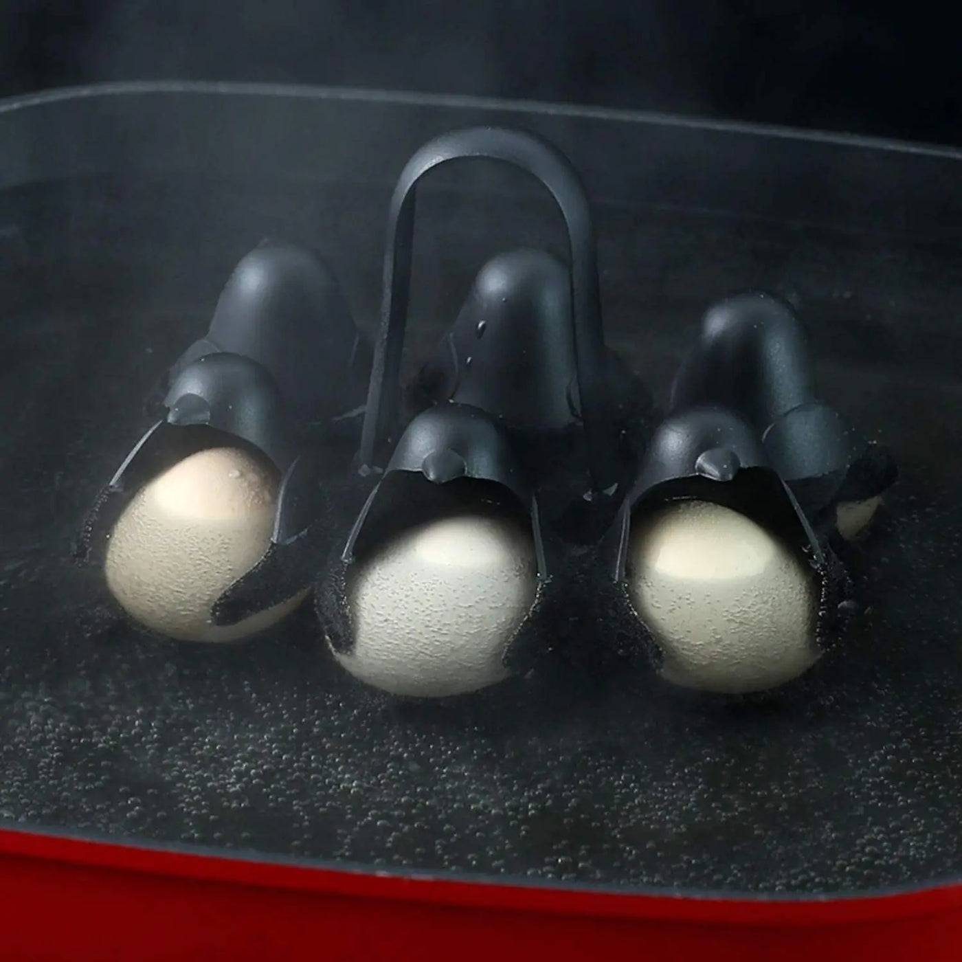 Penguin egg holder cups shown up close with eggs steaming inside a pot