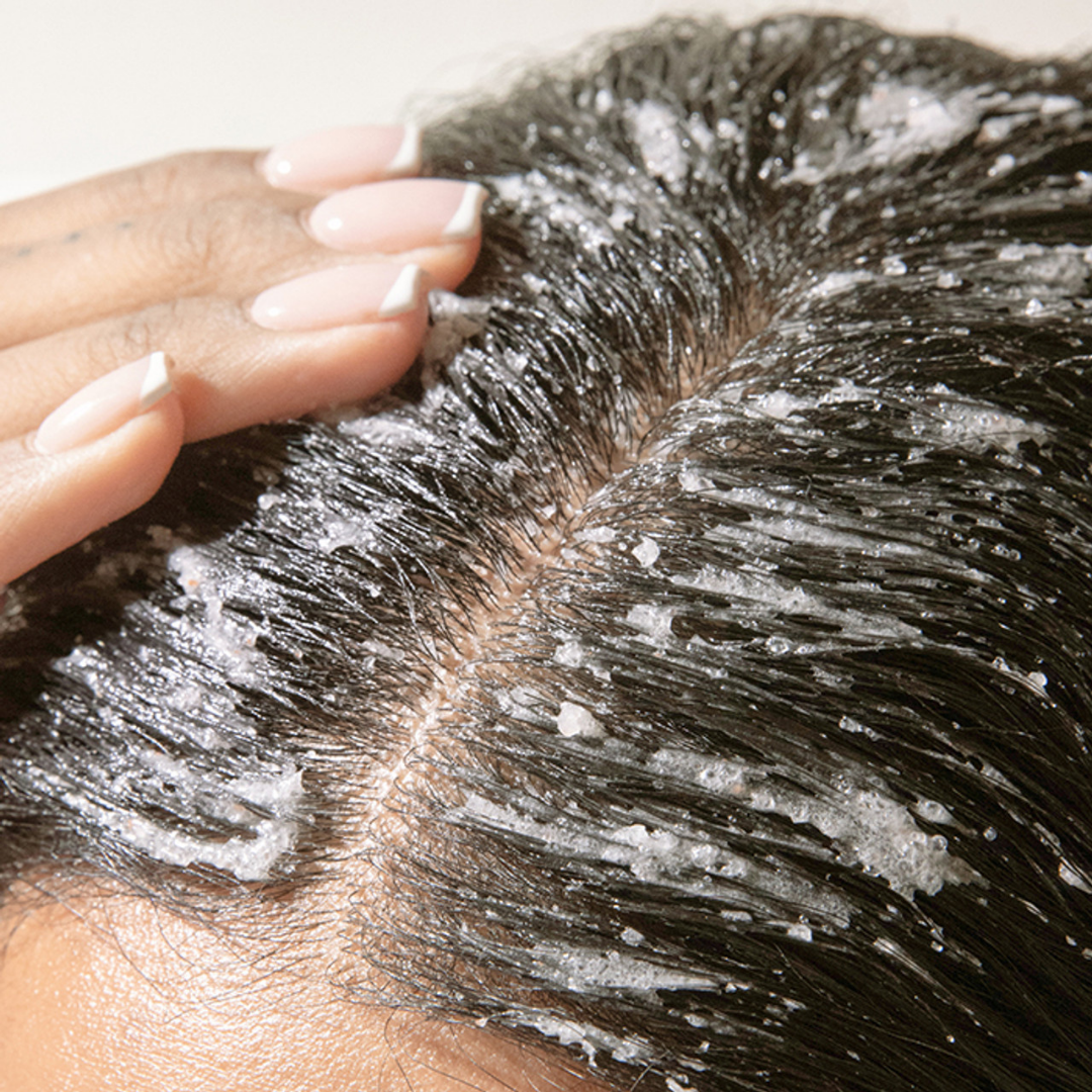 Hands massaging scalp scrub into roots