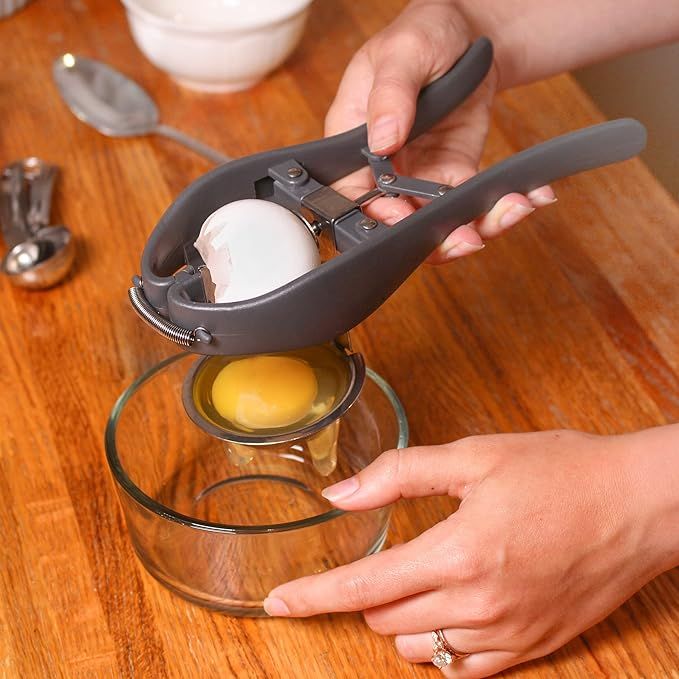 Stainless steel egg separator held in hand to show its compact size