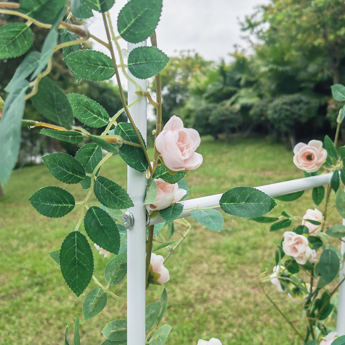 White metal garden arch trellis arbor with climbing plants over walkway - close-up detail