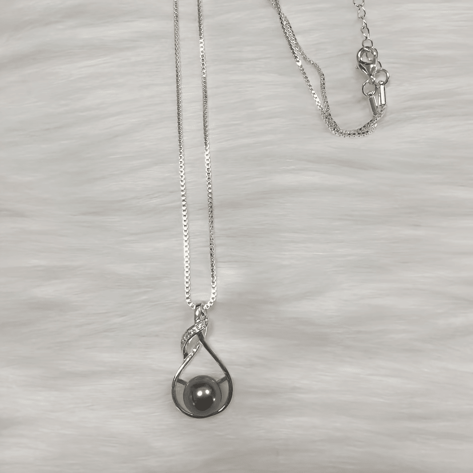 Black pearl necklace flat lay on light background