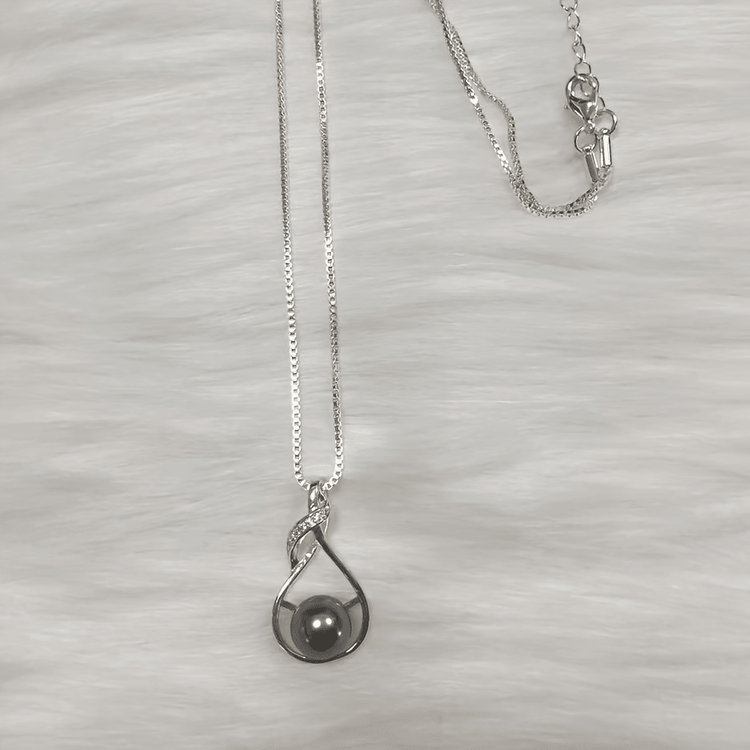 Black pearl necklace flat lay on light background