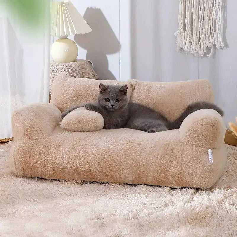 Miniature tan plush sofa bed for pets with raised armrests, a curved backrest, and a matching bolster pillow