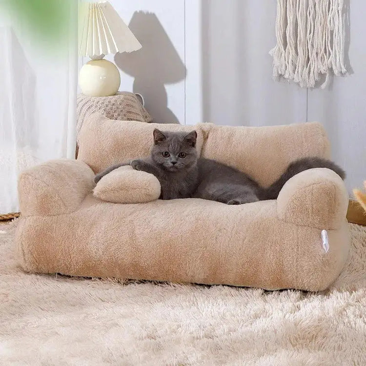 Miniature tan plush sofa bed for pets with raised armrests, a curved backrest, and a matching bolster pillow