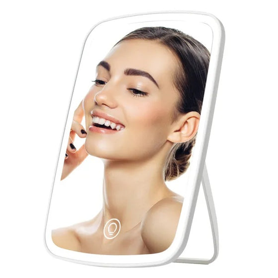 Woman's face reflected in a white lighted vanity makeup mirror on its stand