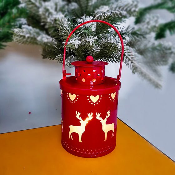 Red Christmas LED lantern with reindeer and tree cutouts on a wooden table