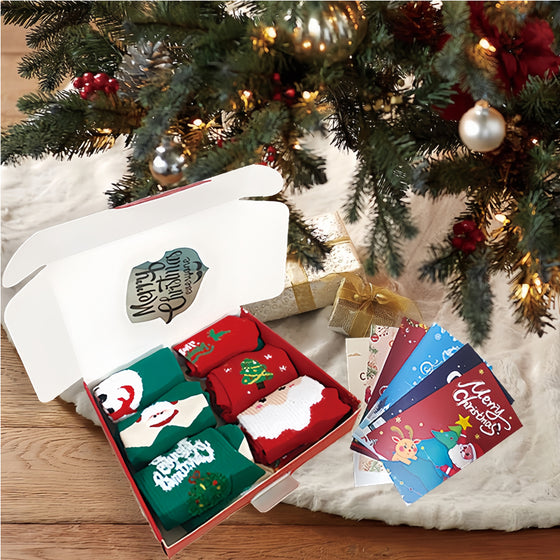 Christmas socks gift set in an open gift box with greeting cards under a Christmas tree