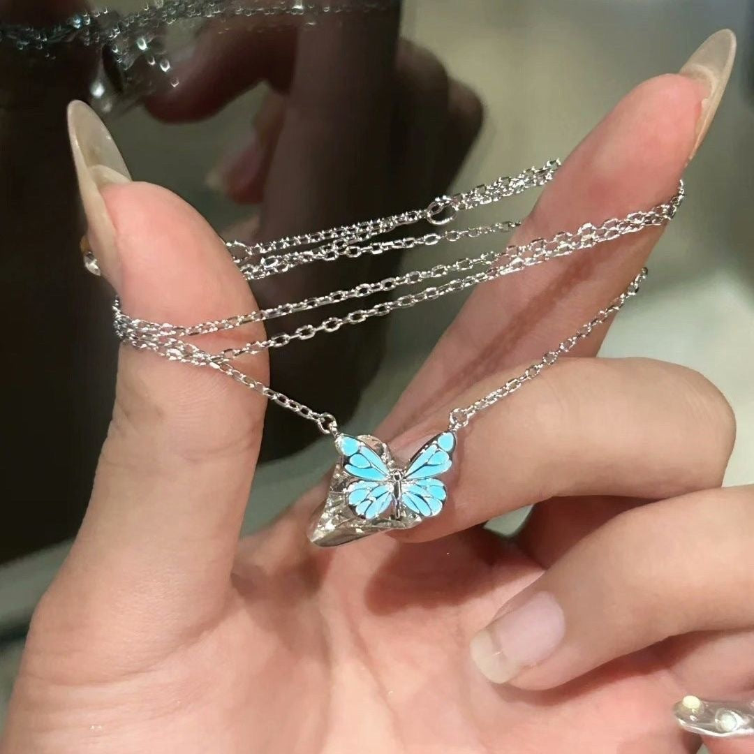 Hand holding a glowing butterfly necklace, not included