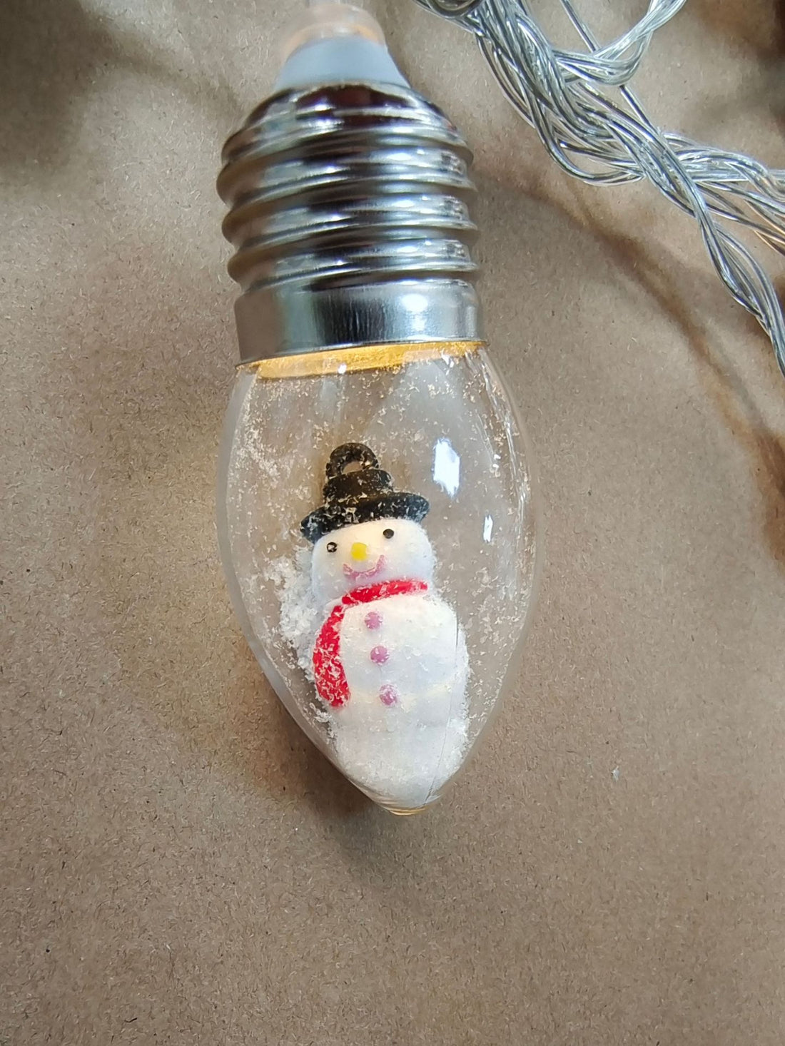 Clear bulb string light with a miniature snowman figure inside