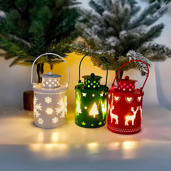 White, green and red Christmas LED candle lanterns lit on a table with holiday greenery