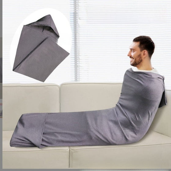 Man wrapped in a gray wearable sleeping bag on a sofa