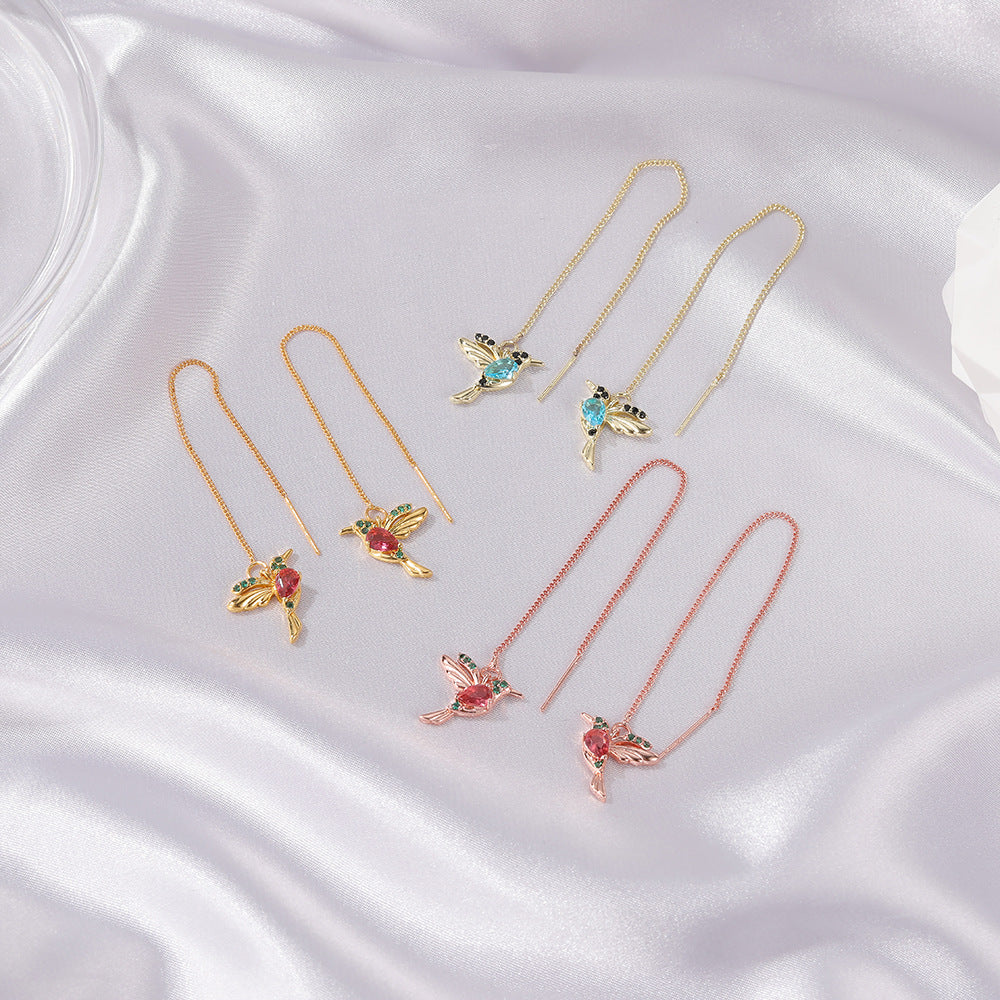 Three pairs of hummingbird earrings on white satin