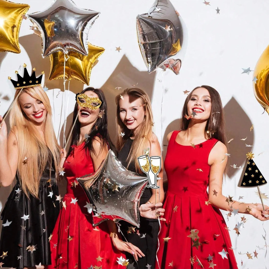 Women at a party holding gold and black photo booth props
