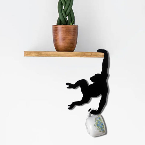 Monkey hook hanging from a wall shelf holding a mug