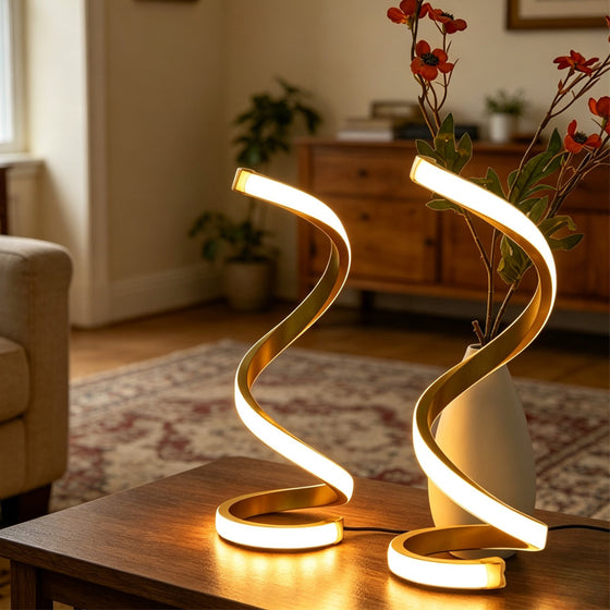 Two golden spiral LED table lamps glowing on a wooden coffee table