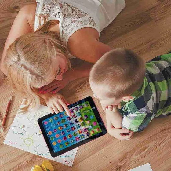 Two children lying on a wood floor playing with the mini learning tablet