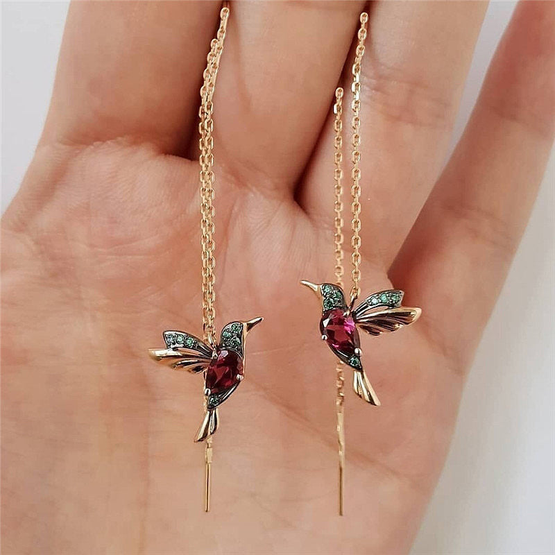 Hand holding hummingbird threader earrings