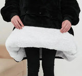 Black plush hoodie-blanket worn as a poncho with a built-in front pocket and sherpa-white fleece lining