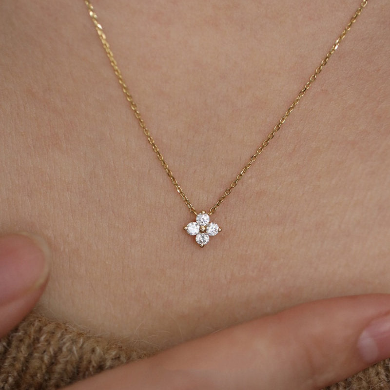 Gold four-leaf clover pendant necklace shown close up on the neck