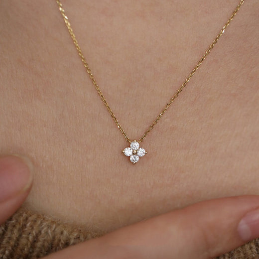 Gold four-leaf clover pendant necklace shown close up on the neck