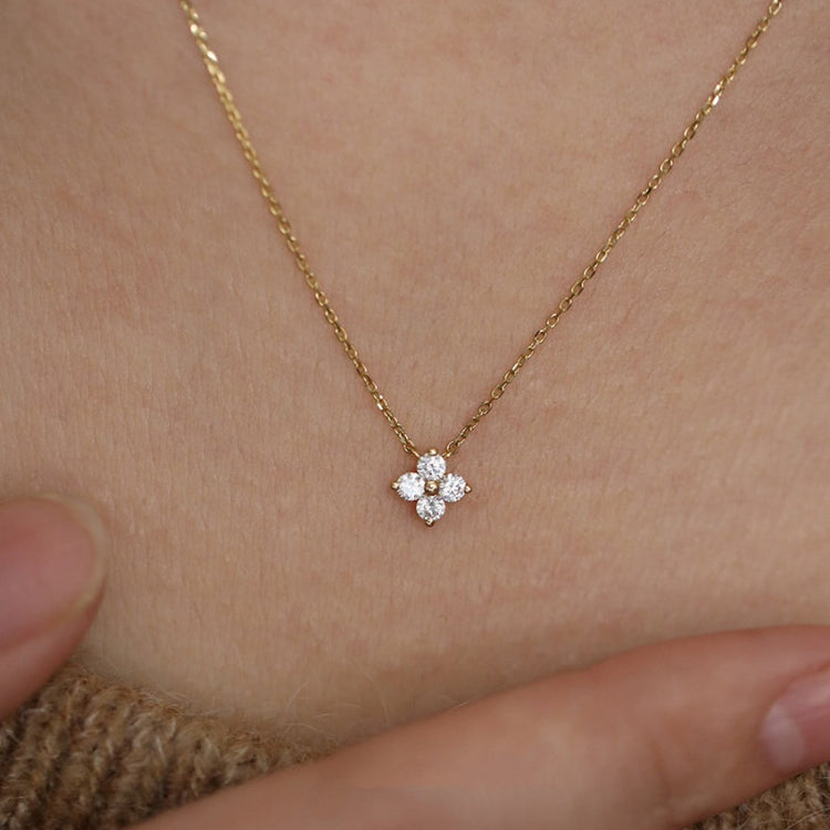 Gold four-leaf clover pendant necklace shown close up on the neck
