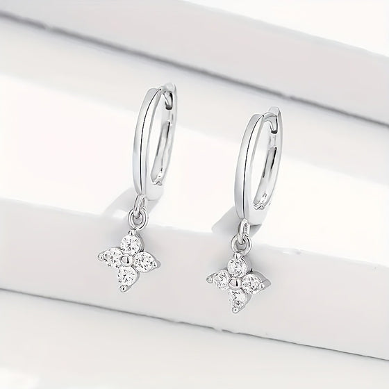 Silver-tone huggie hoop earrings with dangling four-leaf clover charms