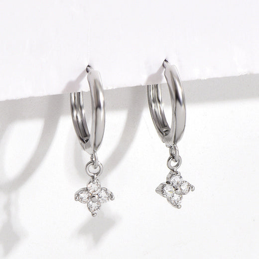Close-up of silver-tone four-leaf clover charm earrings with clear stone accents