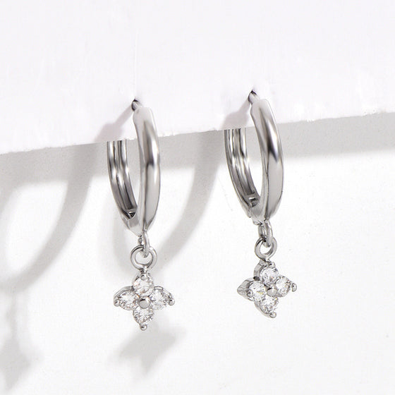 Close-up of silver-tone four-leaf clover charm earrings with clear stone accents