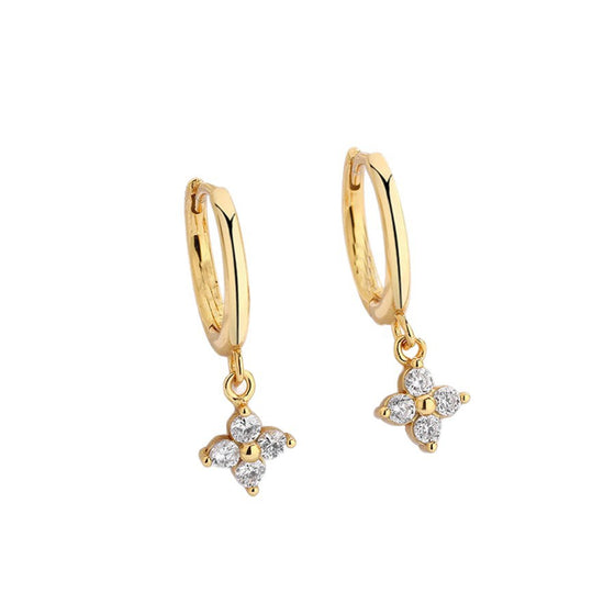Gold-tone four-leaf clover charm huggie hoop earrings on a white background