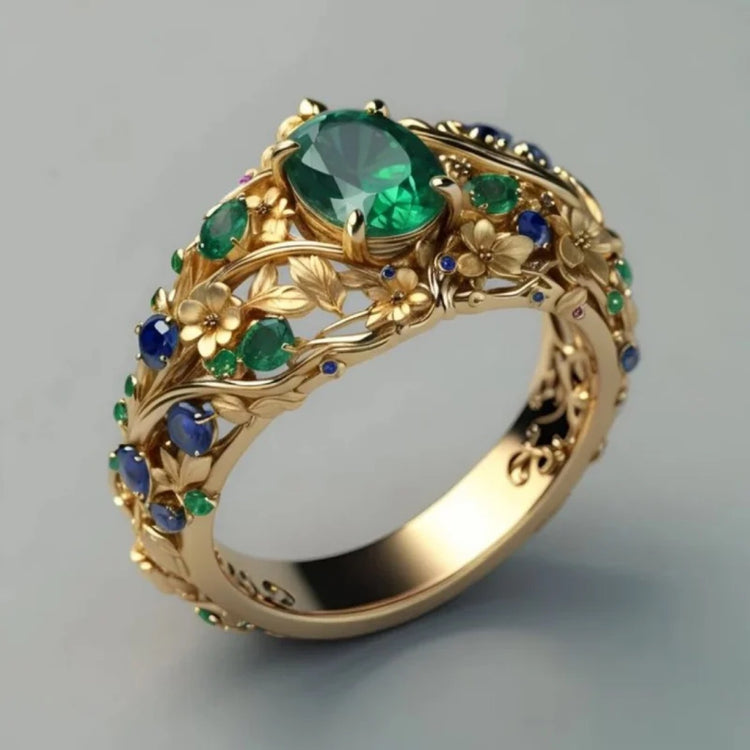 Close-up of gold-tone carved ring showing the floral vine design with green and blue zircon stones