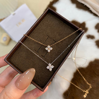 Gold and white gold four-leaf clover pendant necklaces in a jewelry gift box