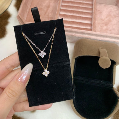 Gold four-leaf clover pendant necklace displayed on a velvet card with jewelry pouch