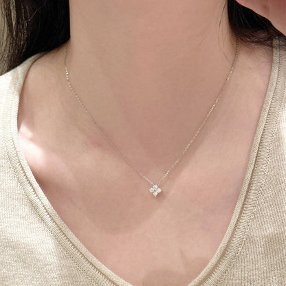 Close-up of the white gold four-leaf clover pendant resting on the collarbone