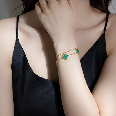 Four-leaf clover charm bracelet in green, worn on wrist with gold-tone chain