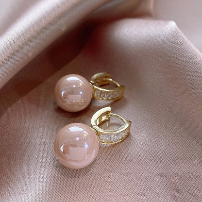 Pair of Simple Light Luxury Ear Buckle earrings in pink pearl with gold crystal pave hoops, flat lay