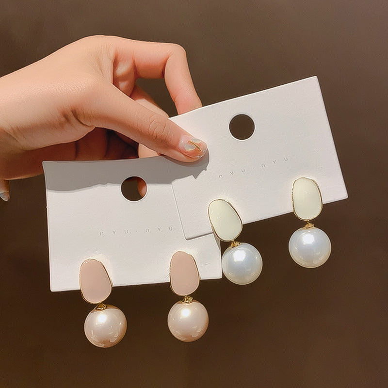 Hand holding pink pearl drop stud earrings on a jewelry card, Silver Needle-Pink Pearl color