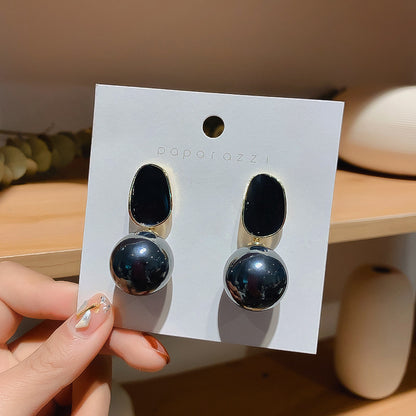 Hand holding dark stone drop stud earrings on a jewelry card, alternate color shown