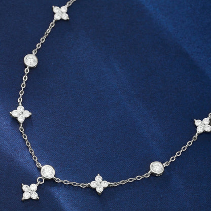 Sterling silver clover and star charm anklet chain laid flat on blue fabric