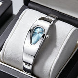 Silver stainless steel water drop watch with blue teardrop dial, front view on jewelry cushion